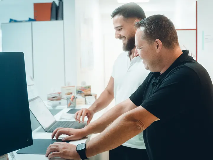 Semi Kochta und Jörg Goßler arbeiten am Empfangstresen der Praxis am Laptop